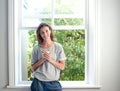 Relaxed woman smiling with cup of coffee by window at home Royalty Free Stock Photo