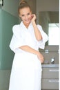 Relaxed woman standing in white bathrobe