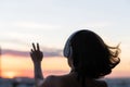Relaxed woman with streaming hair wearing headphones listening to music on the beach at sunset. Back view, silhouette lonely girl Royalty Free Stock Photo