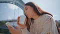 Relaxed woman surfing phone at sunny river bank closeup. Girl sipping coffee Royalty Free Stock Photo