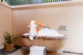 Relaxed woman with towel on head sitting in stone outdoor bath. Sexy girl taking bathtub with bubbles and foam. Back Royalty Free Stock Photo