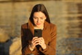 Relaxed woman using cell phone in winter at sunset Royalty Free Stock Photo