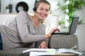 relaxed woman wearing headset and using laptop by open folder Royalty Free Stock Photo