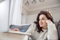 A relaxed woman in white sweater lying on the sofa and watching something online Royalty Free Stock Photo