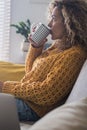 Relaxed and worried adult woman at home with paper and pen and computer laptop sit down on the sofa thinking and. drinking Royalty Free Stock Photo