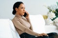 Relaxed young African American woman using crucial mobile phone on sofa couch Royalty Free Stock Photo