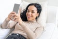 Relaxed young African American woman using crucial mobile phone on sofa couch Royalty Free Stock Photo