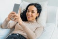 Relaxed young African American woman using crucial mobile phone on sofa couch Royalty Free Stock Photo