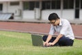 Relaxed young Asian business man working with laptop on green grass Royalty Free Stock Photo