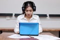 Relaxed young Asian business woman with headphones working with laptop in office. Royalty Free Stock Photo