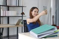 Relaxed young Asian business woman taking a picture or selfie in office Royalty Free Stock Photo