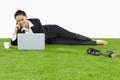 A relaxed young Asian businesswoman lying on grass using her laptop. Conceptual image Royalty Free Stock Photo