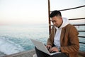 Relaxed young Asian man using laptop on the beach. Royalty Free Stock Photo