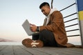 Relaxed young Asian man using laptop on the beach. Royalty Free Stock Photo