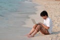 Relaxed young Asian man using laptop on the sandy of beach. Summer holiday. Royalty Free Stock Photo