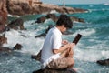 Relaxed young Asian man using laptop at sea shore. Summer holiday. Royalty Free Stock Photo