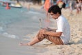 Relaxed young Asina man traveler with laptop sitting on the sandy of beach. Vacations summer concept. Royalty Free Stock Photo