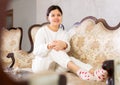 Relaxed young brunette sitting on soft antique sofa at home