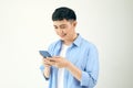 Relaxed young casual man reading text message on mobile phone isolated over white studio background Royalty Free Stock Photo