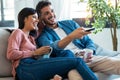 Relaxed young couple changing channels with the remote control while watching TV on the sofa at home Royalty Free Stock Photo