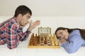 Relaxed young couple playing chess at home lying on sofa. won - Friendship.