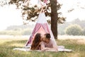 Relaxed young couple sitting near wigwam in park on sunny day. summer holiday vacation. man and woman are hugging and Royalty Free Stock Photo