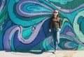 Relaxed young female in jeans and sunglesses near multicolored graffiti wall on Belgrade city street, Serbia