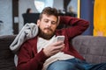 Relaxed young man lying on sofa and using cellphone Royalty Free Stock Photo