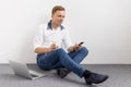 Relaxed young man sitting on floor and using mobile phone Royalty Free Stock Photo