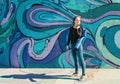 Relaxed young smiling female in jeans and blue jacket near graffiti wall on Belgrade city street, Serbia Royalty Free Stock Photo