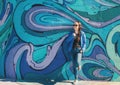 Relaxed young smiling female in jeans and blue jacket near graffiti wall on Belgrade city street, Serbia Royalty Free Stock Photo