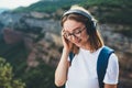 Relaxed young traveler woman hipster meditates with eyes closed listening to favorite music on wireless headphones while standing Royalty Free Stock Photo