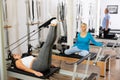 Relaxed young woman doing exercise for lower back on Pilates chair equipment during workout in rehabilitation center Royalty Free Stock Photo