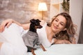 Relaxed young woman and her dog spending time in bed Royalty Free Stock Photo