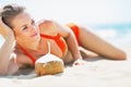 Relaxed young woman laying on beach with coconut Royalty Free Stock Photo