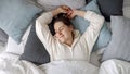 Relaxed young woman lying on soft pillows and stretching in bed at morning. Concept of comfort, relaxation, healthy sleeping and Royalty Free Stock Photo