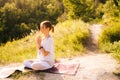 Relaxed young woman is meditating in lotus position with closed eyes sitting on yoga mat. Royalty Free Stock Photo