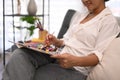 Relaxed young woman sitting on couch and painting picture with watercolor. Art, creative hobby and leisure activity Royalty Free Stock Photo