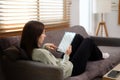 Relaxed young woman surfing internet on digital tablet in living room Royalty Free Stock Photo