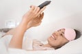 Relaxed young woman using a smartphone in the morning on the bed at home. Happy and smiling girl using a mobile phone Royalty Free Stock Photo