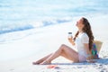 Relaxed woman on ocean coast drinking coffee while sitting