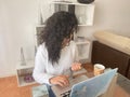 Relaxed young woman working on her laptop from home sipping a warm drink from her favorite mug and looking at her fingers. Royalty Free Stock Photo