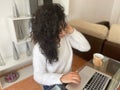 Telecommuting concept. Relaxed young woman working on her laptop from home sipping a warm drink from her favorite mug while Royalty Free Stock Photo