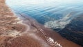 Relaxeing natural wallpaper with sea comb and tranqui water reflecting blue sky. Ripples on sea surface and sand