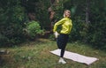 Relaxing activity with stretch arms and legs. Young fit woman doing stretching exercises  training outside in green park Royalty Free Stock Photo