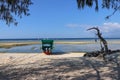 Relaxing atmosphere on the ocean shore. White fine sand and tethered fishing boat offshore at low tide time. Wooden boat.