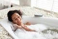 Relaxing bath. Happy young woman lying in bathtub with closed eyes, enjoying beauty ritual at luxury spa, copy space Royalty Free Stock Photo