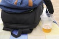 Relaxing on the beach, there is a drunk glass of beer, next to a backpack