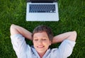 Relaxing fantasy. Top view relaxed mature woman with laptop smiling while lying on grass.