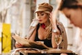 Relaxing girl in elegant attire reading newspaper after work, sitting in cafe with glass of champagne. Portrait of Royalty Free Stock Photo